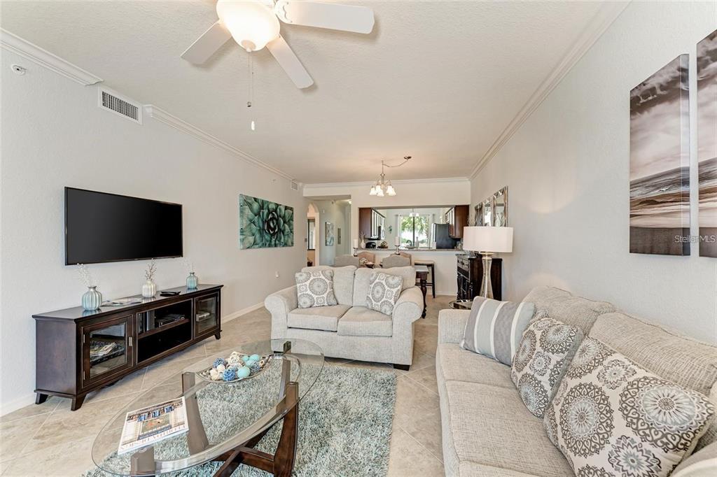 A living room features a television, two sofas, a glass coffee table, and tile flooring — 16706 VARDON TERRACE UNIT 304, BRADENTON, FL