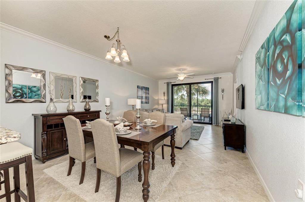 A dining area with a wooden table and chairs sits adjacent to a living room — 16706 VARDON TERRACE UNIT 304, BRADENTON, FL