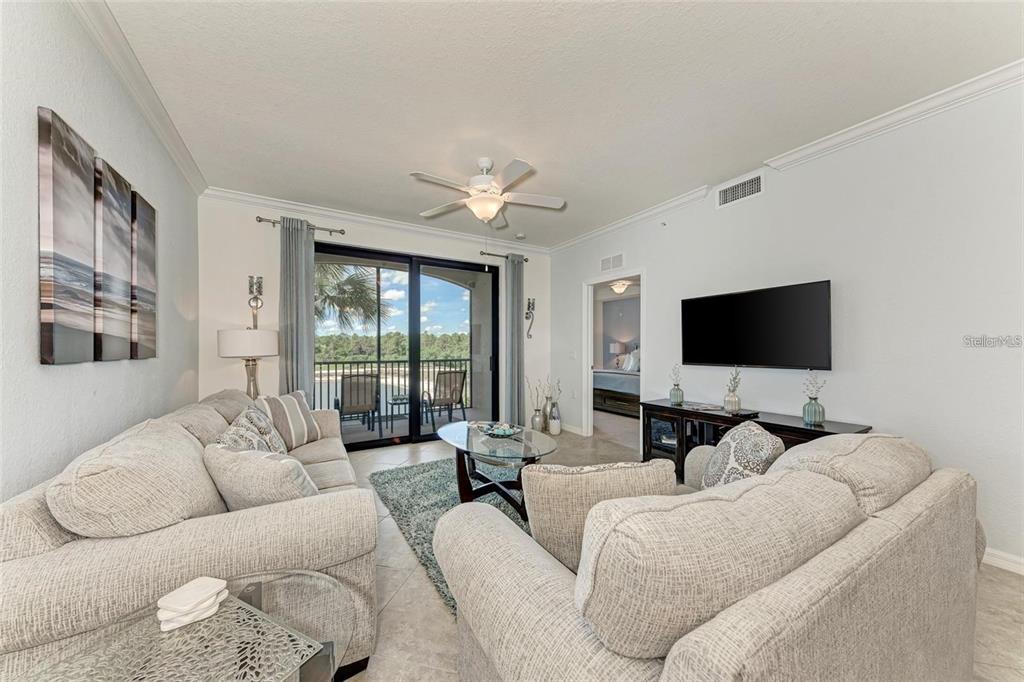 A living room features light-colored sofas, a glass coffee table, and a sliding door to a balcony — 16706 VARDON TERRACE UNIT 304, BRADENTON, FL