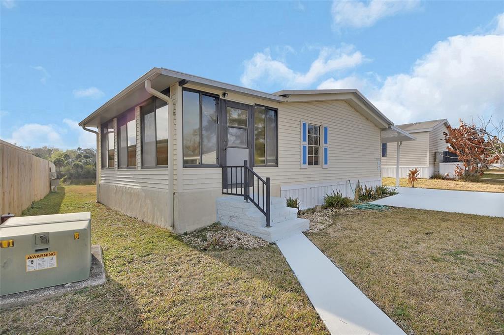 A light-colored manufactured home features a screened-in front porch and a concrete walkway — 2008 HICKORYWOOD DRIVE, SOUTH DAYTONA, FL