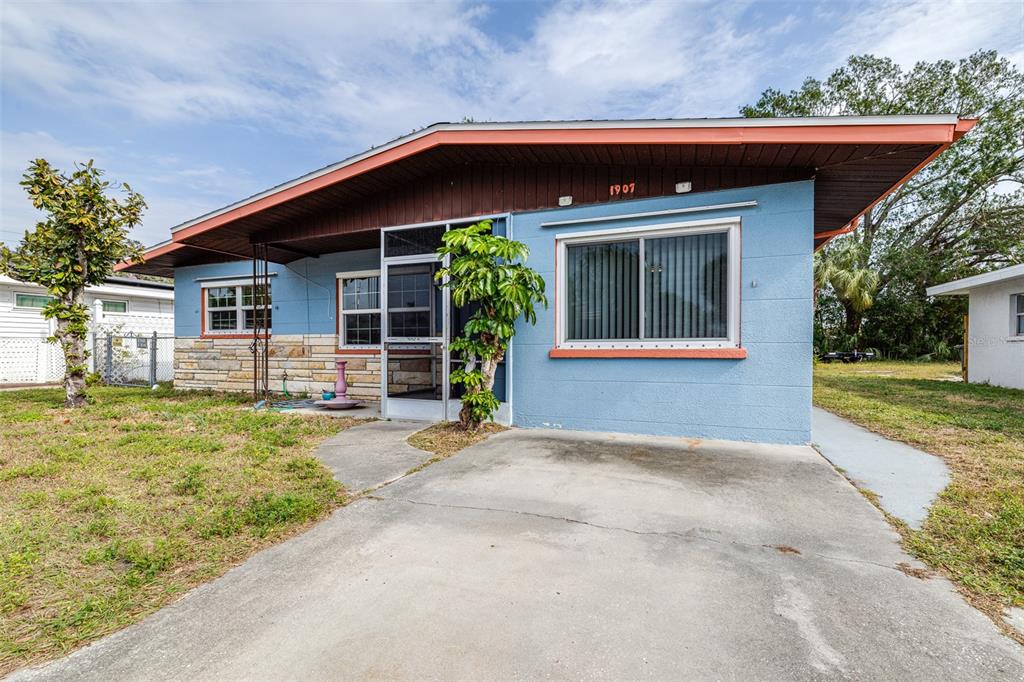 A blue single-story house with a stone facade, a concrete driveway, and a screened entryway — 1907 27TH STREET W, BRADENTON, FL