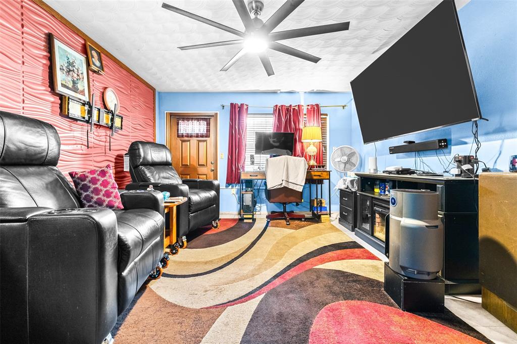A living room features black leather recliners, a patterned area rug, and a wall-mounted television — 1907 27TH STREET W, BRADENTON, FL