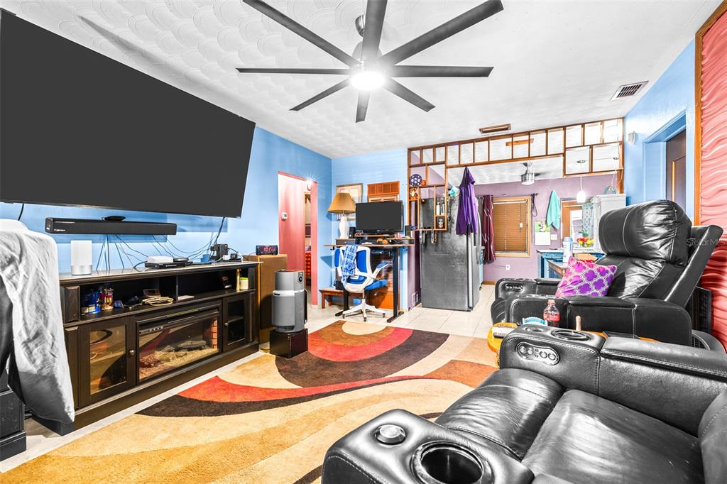 A living room features a large television, black leather recliners, and a patterned area rug — 1907 27TH STREET W, BRADENTON, FL