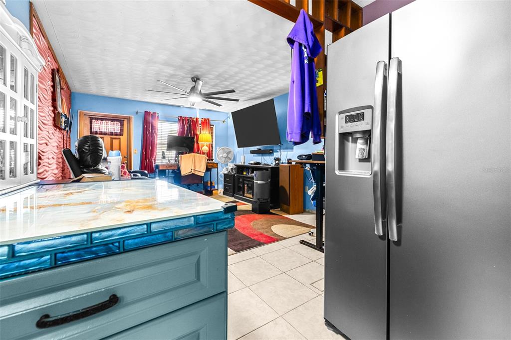 A kitchen island with a blue base and marble countertop sits before a living area — 1907 27TH STREET W, BRADENTON, FL