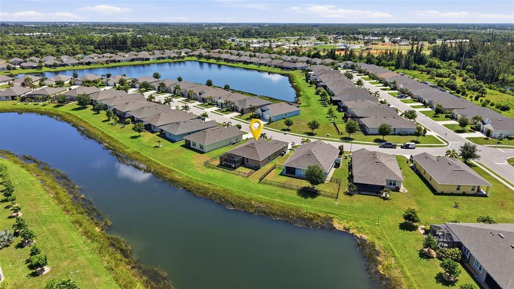 An aerial view shows a suburban neighborhood with houses situated along a winding lake — 7081 WATERFORD PARKWAY, PUNTA GORDA, FL