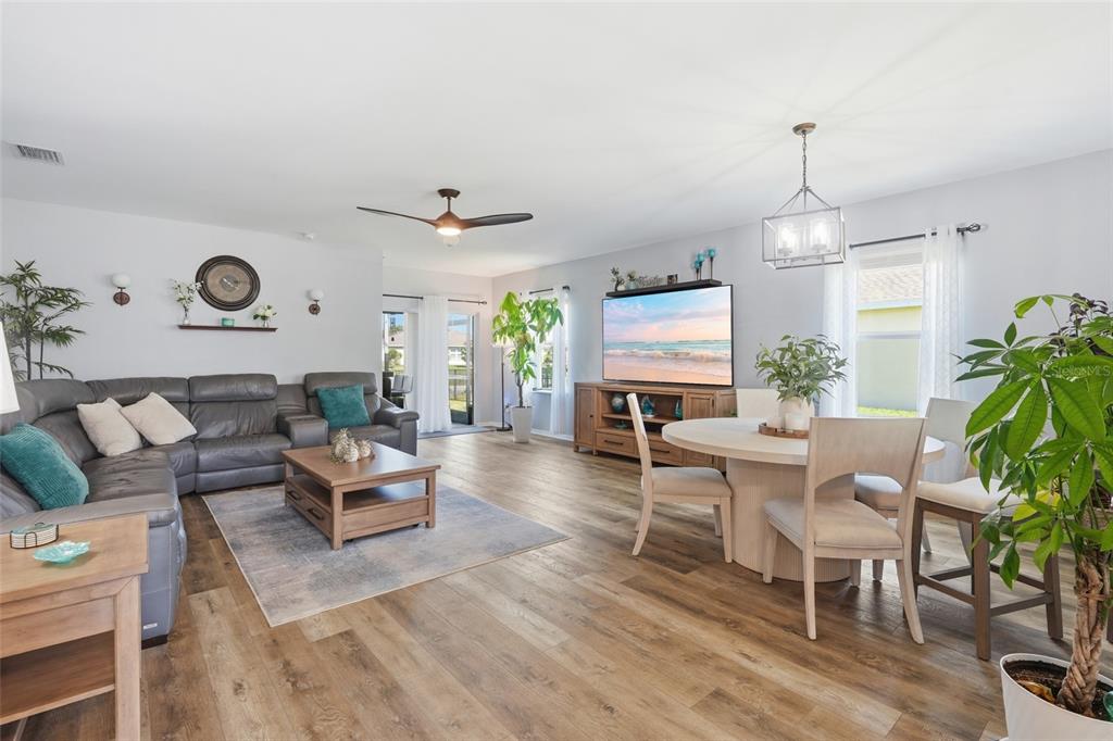 A living and dining area features wood-look flooring, a gray sectional, and a round table — 7081 WATERFORD PARKWAY, PUNTA GORDA, FL