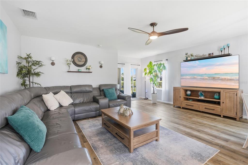 A living room features a grey sectional sofa, a wooden coffee table, and a large television — 7081 WATERFORD PARKWAY, PUNTA GORDA, FL