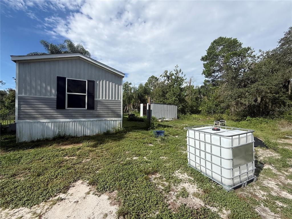 An exterior view of a manufactured home with a large water storage tank nearby — 10305 REVELL ROAD, PARRISH, FL
