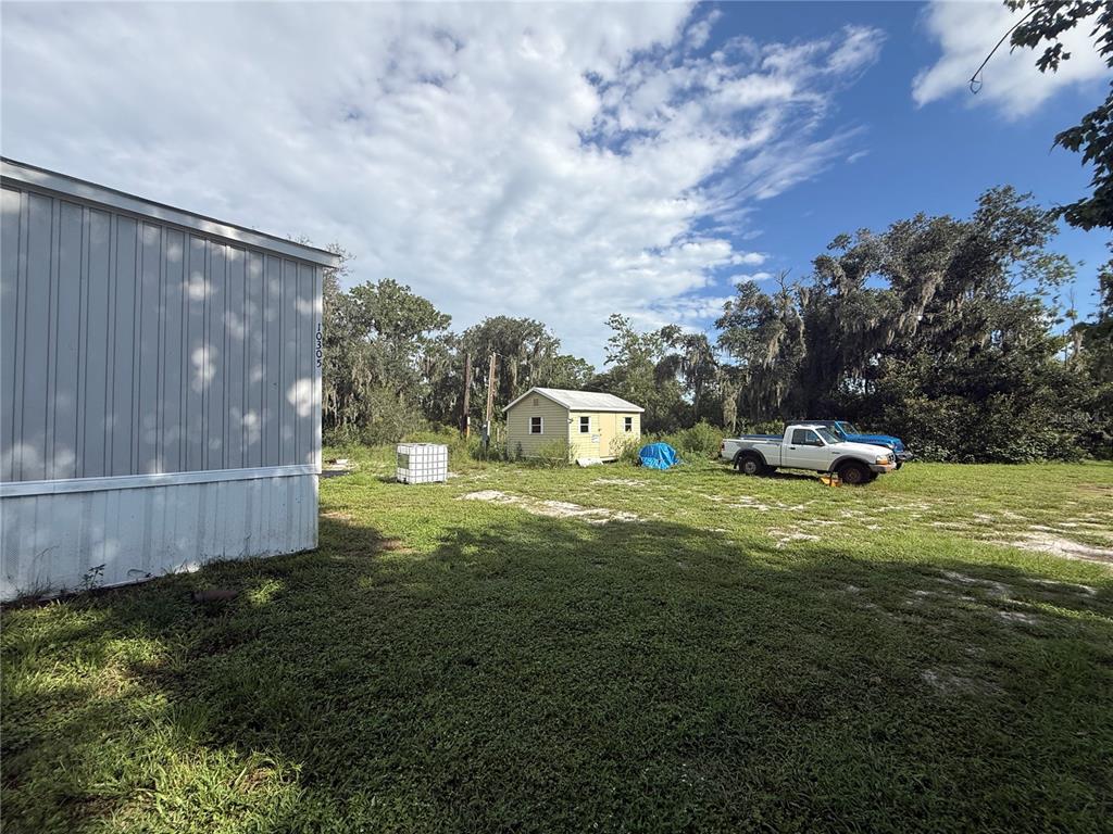 A grassy yard features a mobile home, a small shed, and two parked pickup trucks — 10305 REVELL ROAD, PARRISH, FL