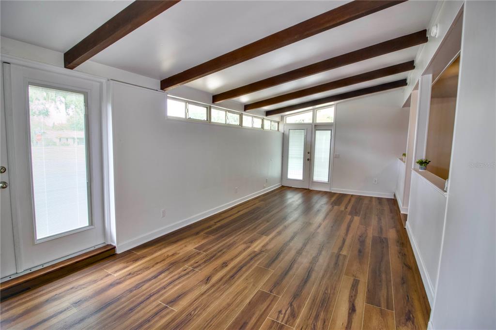 A sunroom features wood-look flooring, exposed ceiling beams, and multiple glass doors and windows — 1114 OAK DRIVE, LEESBURG, FL