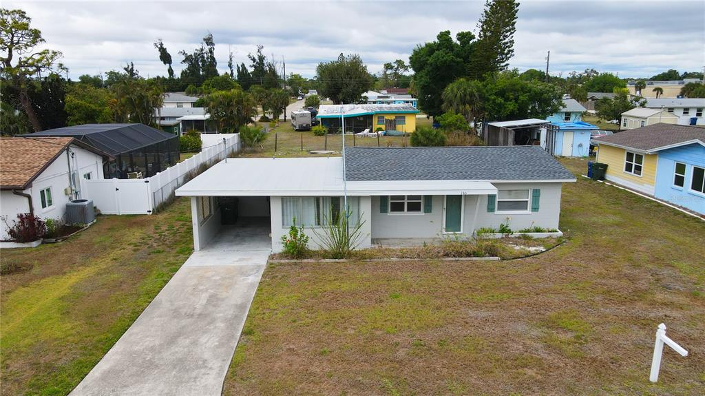 An exterior view of a single-story house with a carport and a large front yard — 130 VIRGINIA COURT, ENGLEWOOD, FL