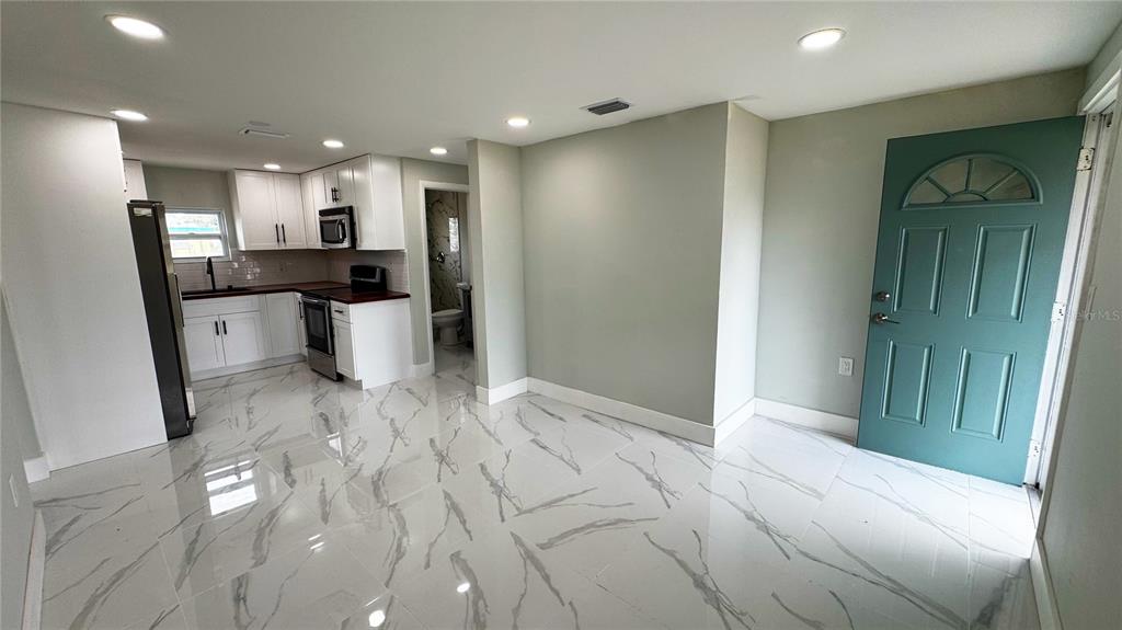 A dining area with a wooden table and chairs sits on white marble-patterned tile flooring — 130 VIRGINIA COURT, ENGLEWOOD, FL