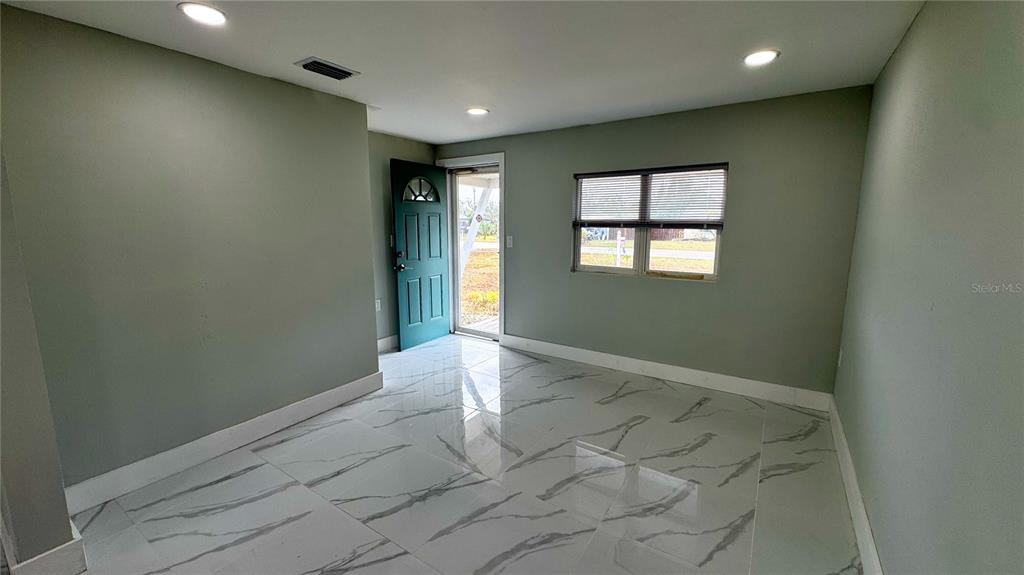 A kitchen and dining area feature white cabinets, dark countertops, and white marble-patterned tile floors — 130 VIRGINIA COURT, ENGLEWOOD, FL