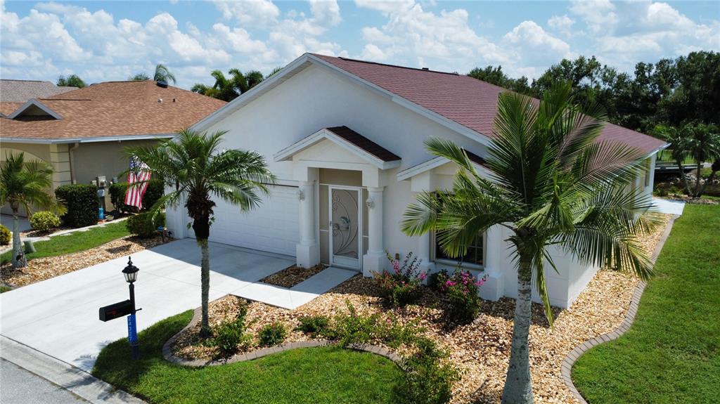 A single-story white house with a brown roof, a palm tree, and a gravel yard — 24327 BUCKINGHAM WAY, PUNTA GORDA, FL