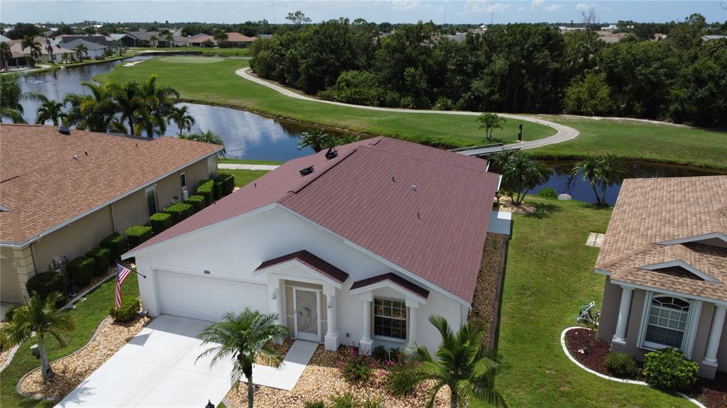 An aerial view shows a white house with a red roof near a golf course — 24327 BUCKINGHAM WAY, PUNTA GORDA, FL