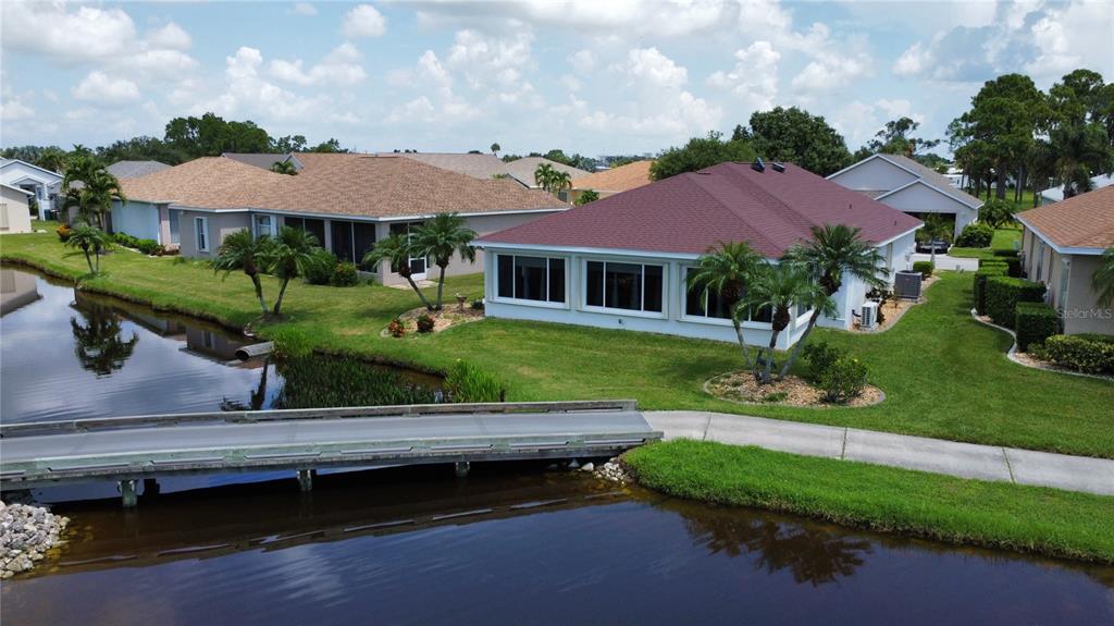 An aerial view of a house with a red roof next to a canal and bridge — 24327 BUCKINGHAM WAY, PUNTA GORDA, FL