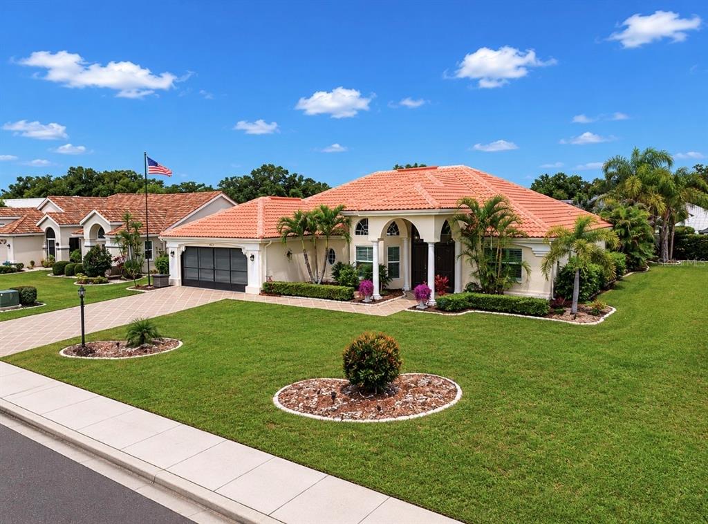 A single-story house with a terracotta tile roof, a two-car garage, and a landscaped lawn — 2027 NEW BEDFORD DRIVE, SUN CITY CENTER, FL