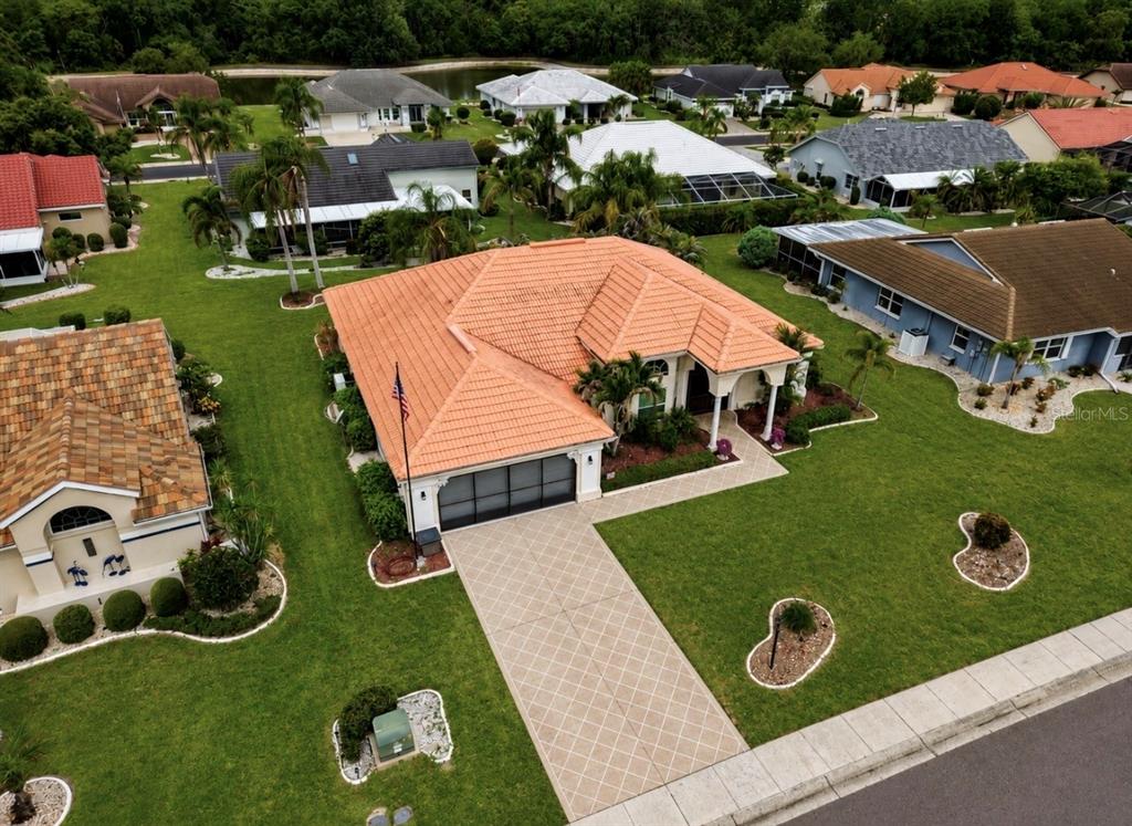 An aerial view shows a single-story house with a terracotta tile roof and paved driveway — 2027 NEW BEDFORD DRIVE, SUN CITY CENTER, FL