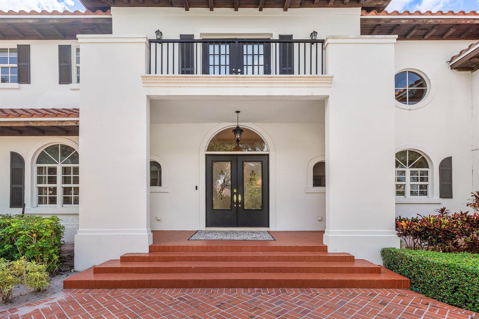 The exterior of a white stucco house features a brick staircase leading to double doors — 2 Firestone Circle, West Palm Beach FL 33401, WEST PALM BEACH, FL