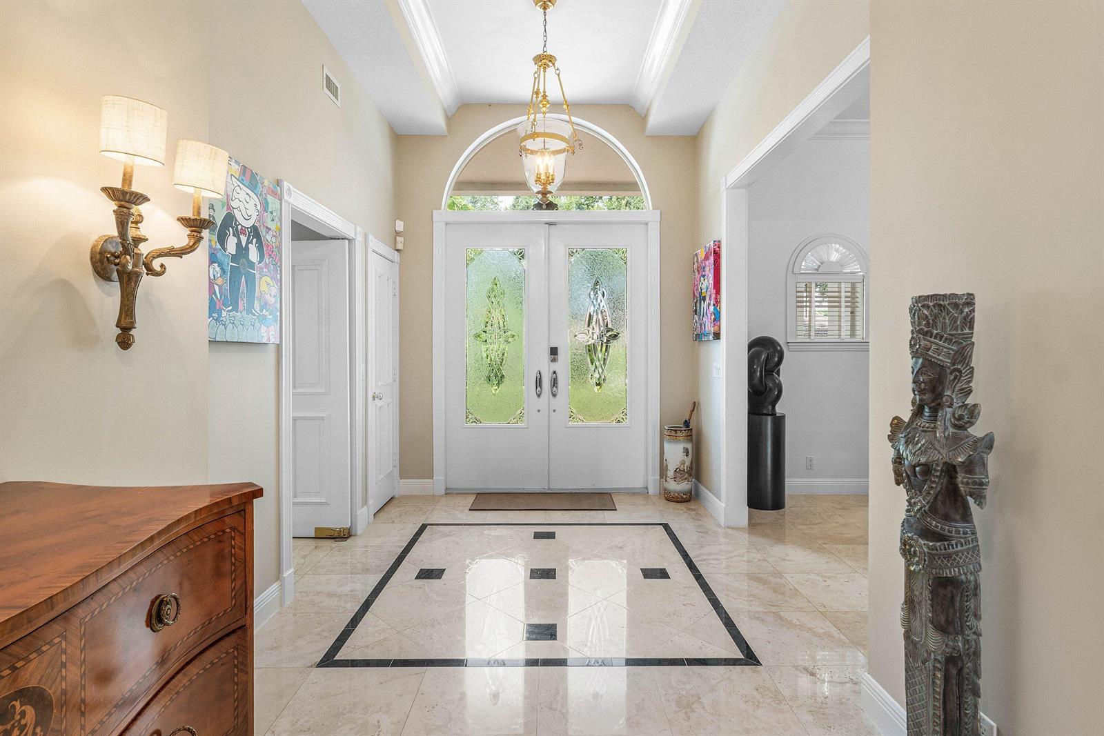 A bright foyer features a double front door, marble tile flooring, and a decorative chandelier — 2 Firestone Circle, West Palm Beach FL 33401, WEST PALM BEACH, FL
