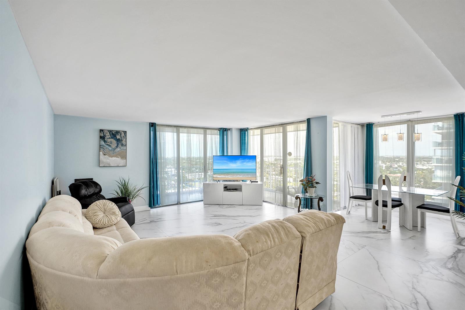 A living and dining area with white marble floors, a curved sofa, and floor-to-ceiling windows — 1010 S Ocean Boulevard # 2009, Pompano Beach FL 33062, POMPANO BEACH, FL