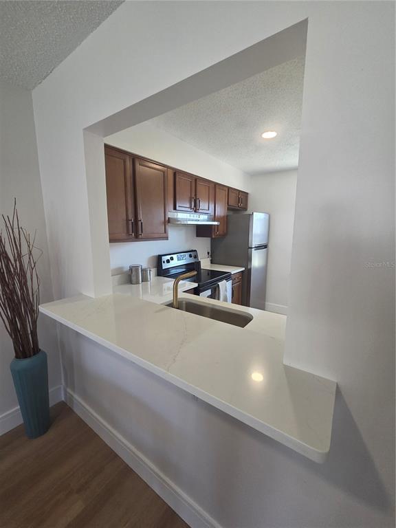 A kitchen with wood cabinets, stainless steel appliances, and a white quartz breakfast bar — 13719 MISSION OAKS BOULEVARD, SEMINOLE, FL