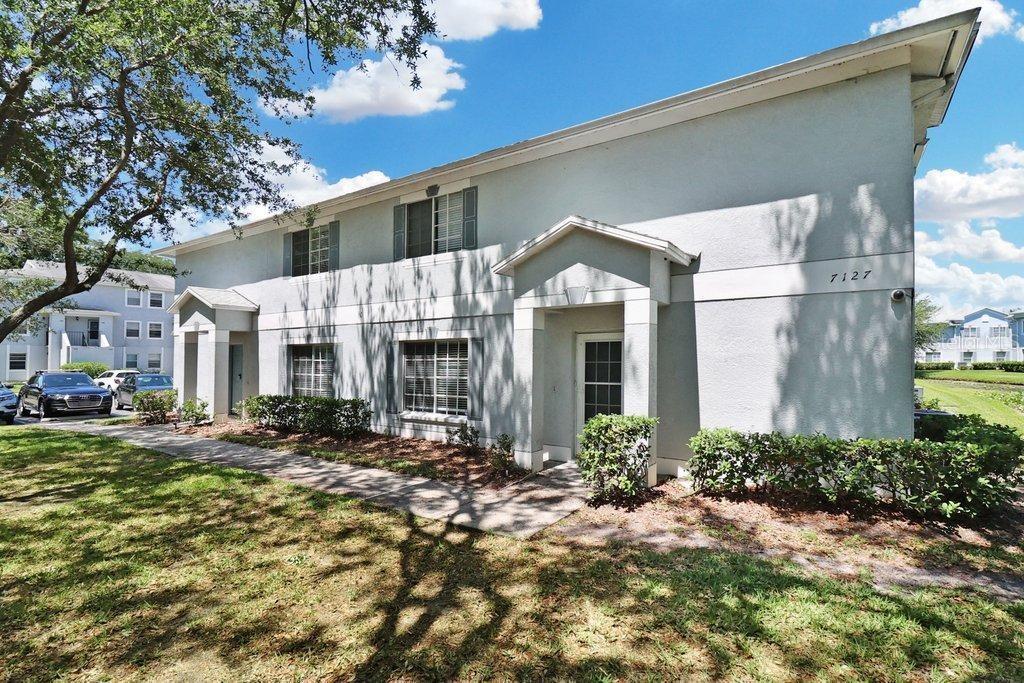 A two-story apartment building exterior with light-colored stucco walls and a sidewalk — 7127 WATERSIDE DRIVE, TAMPA, FL