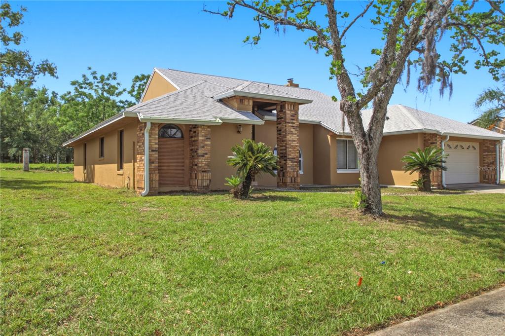 A tan house with a brick-accented entryway, a two-car garage, and a large front lawn — 4649 CREEKVIEW LANE, OVIEDO, FL