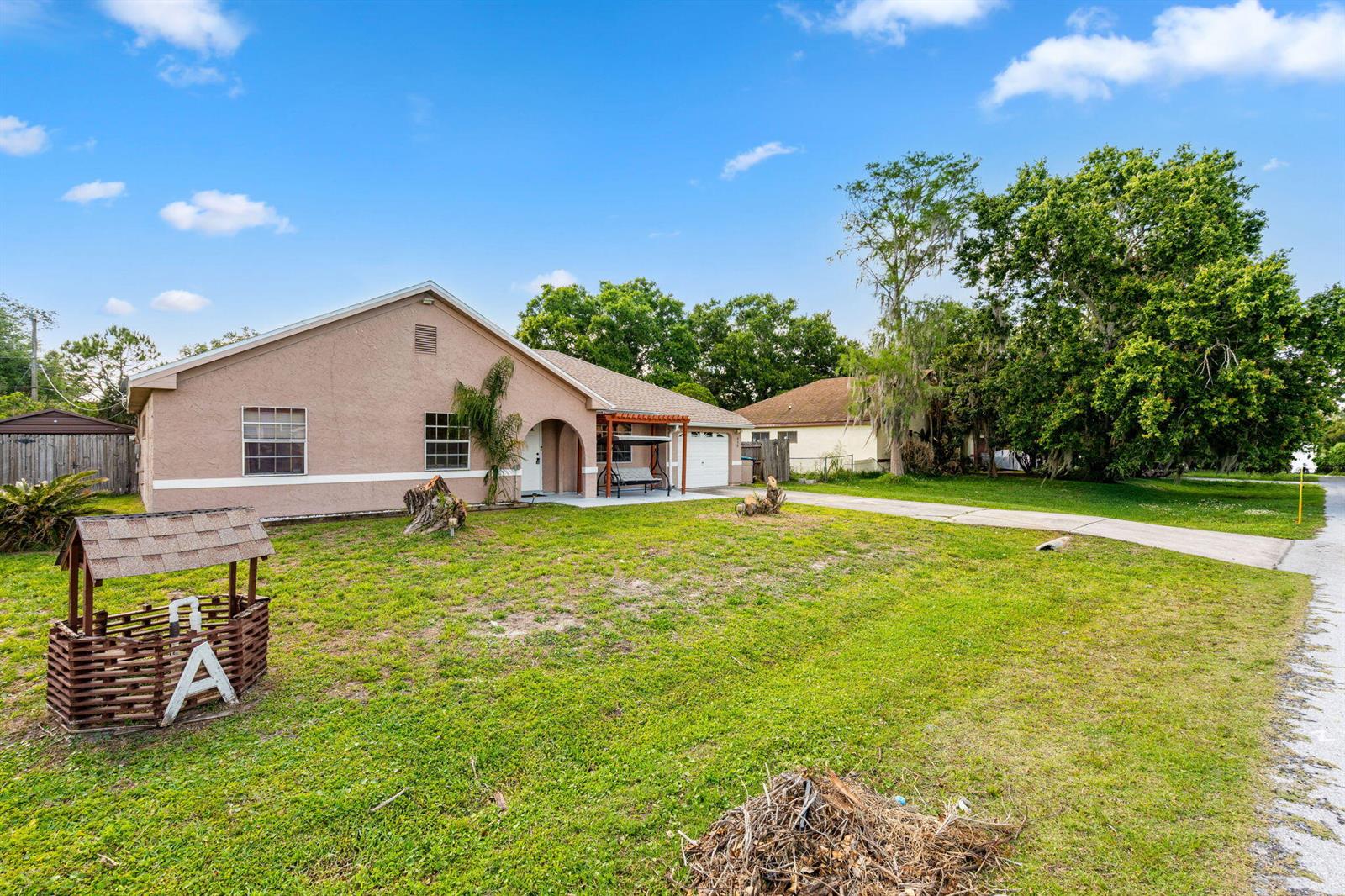 A single-story house with a tan stucco exterior, a front porch, and a decorative well — 950 SE Taft Ave Avenue, Palm Bay FL 32909, PALM BAY, FL