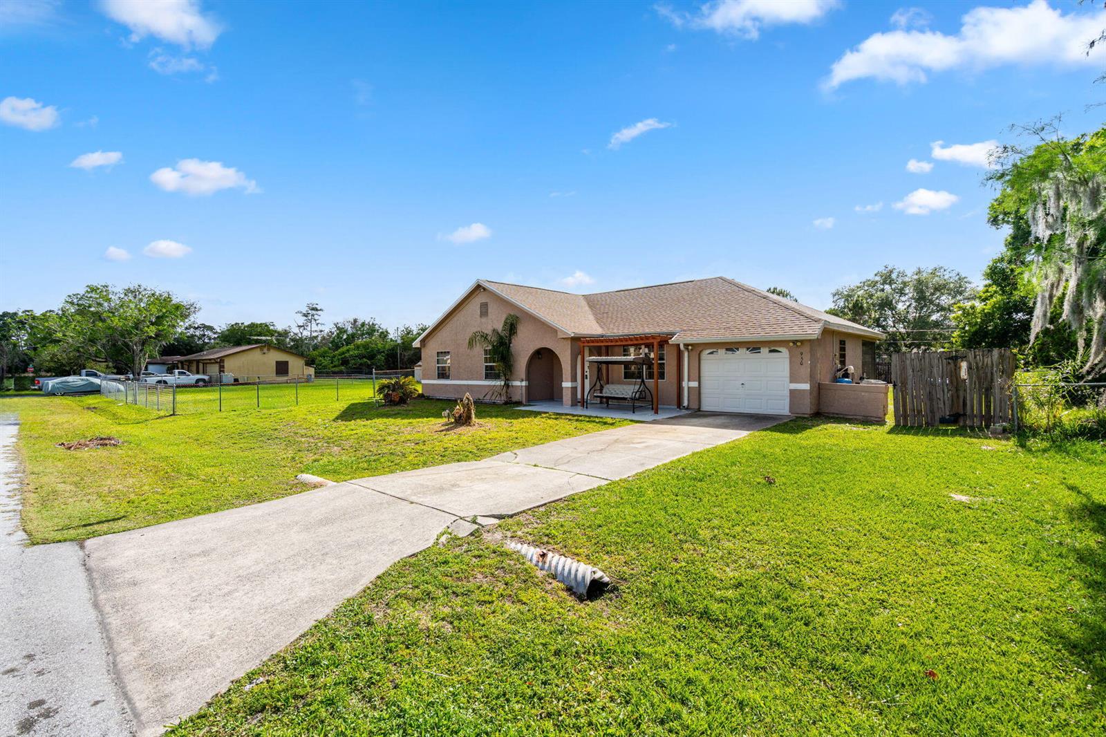 A single-story house with a concrete driveway, a front porch swing, and a garage — 950 SE Taft Ave Avenue, Palm Bay FL 32909, PALM BAY, FL