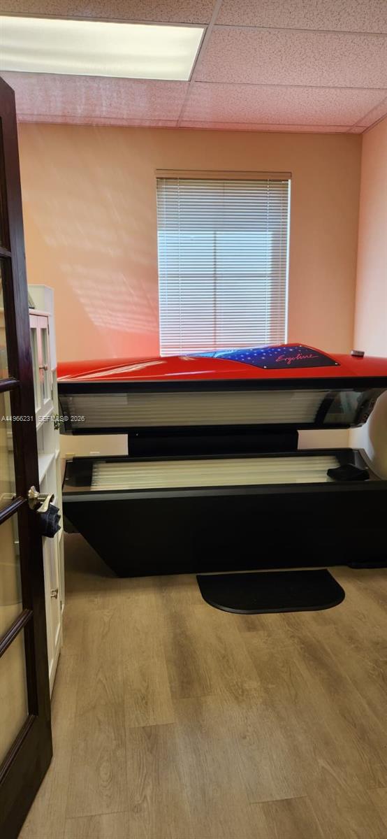A room with light-colored wood flooring contains a red and black tanning bed — orange dr 12505, Davie FL 33330, DAVIE, FL