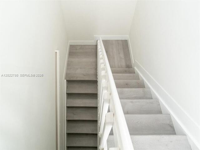 A high-angle view of a staircase with light wood-look steps and a white railing — 9794 W 34th Ct # 0, Hialeah FL 33018, HIALEAH, FL