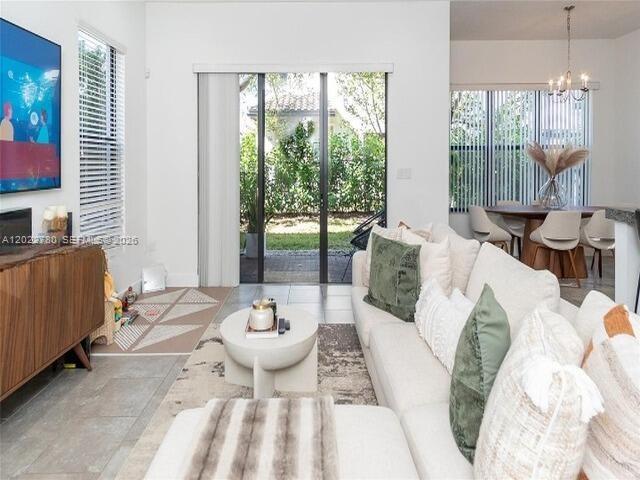 A bright living room features a white sofa, a round coffee table, and sliding glass doors — 9794 W 34th Ct # 0, Hialeah FL 33018, HIALEAH, FL