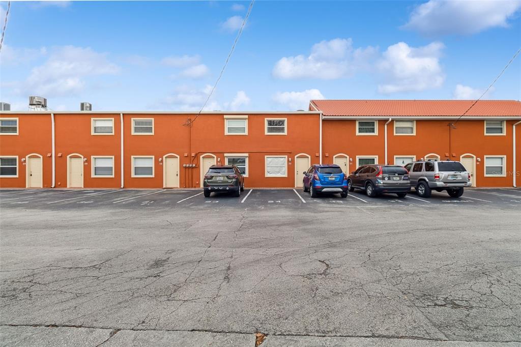 A row of orange townhouses with a parking lot in the foreground — 50 NEEDLE BOULEVARD UNIT 32, MERRITT ISLAND, FL