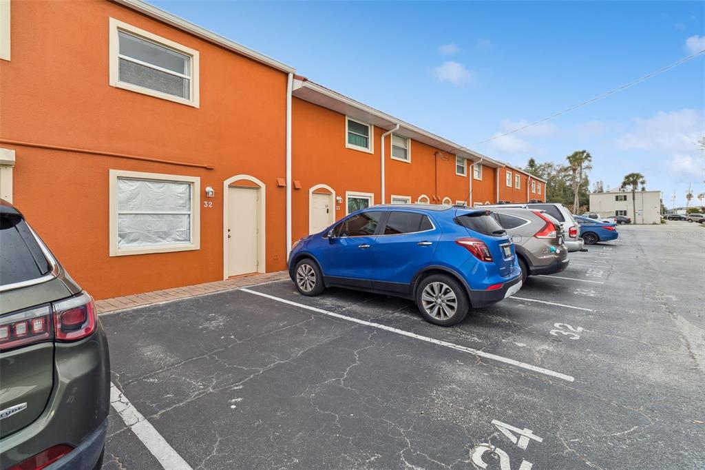 An exterior view shows a row of orange townhouses with a parking lot in front — 50 NEEDLE BOULEVARD UNIT 32, MERRITT ISLAND, FL