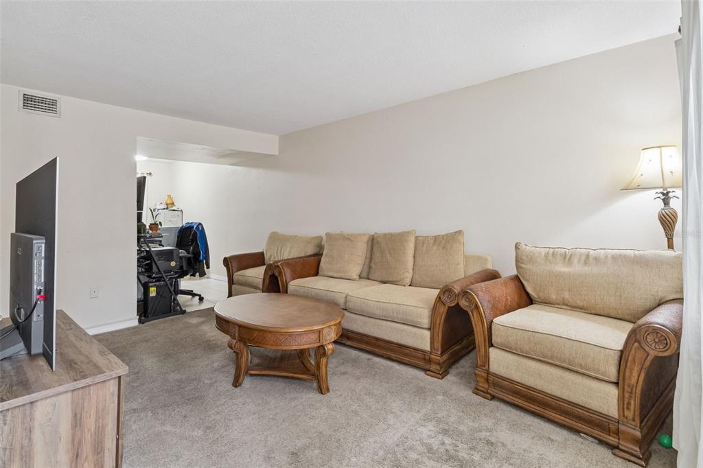 A living room features a beige sofa and two armchairs arranged around a round table — 50 NEEDLE BOULEVARD UNIT 32, MERRITT ISLAND, FL