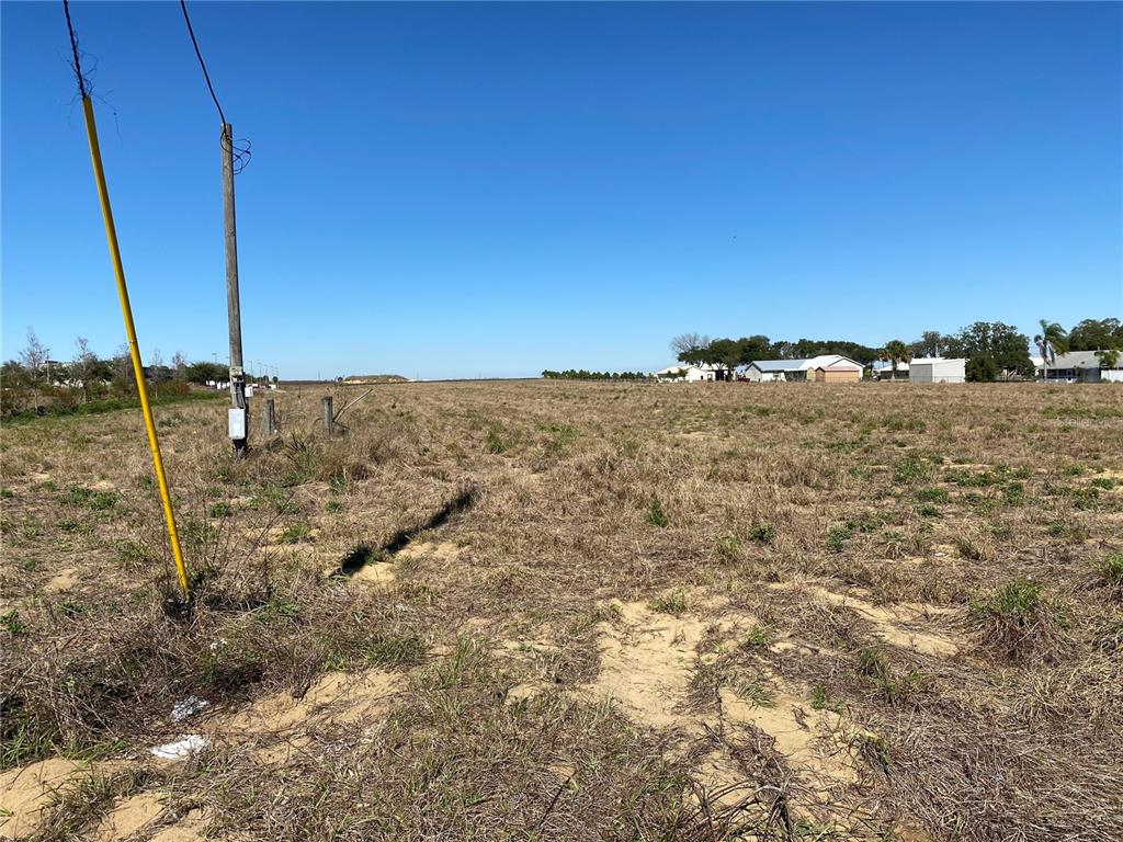 A wide, flat, grassy vacant lot under a clear blue sky with utility poles nearby — US HWY 544 E, HAINES CITY, FL