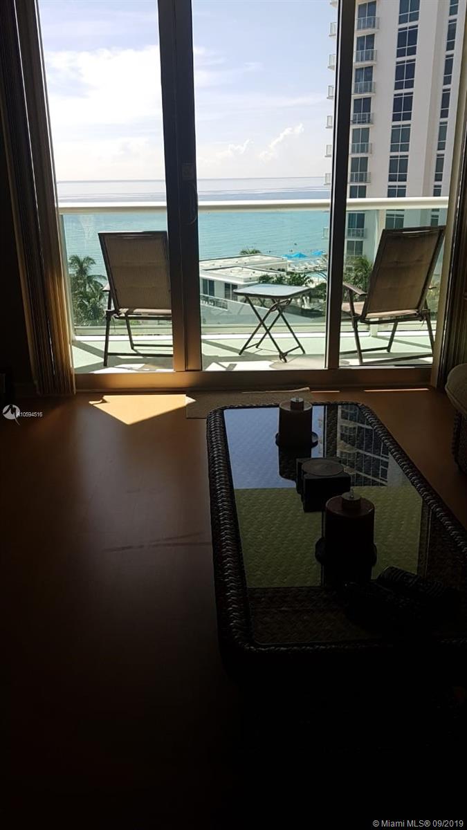 A living room features a glass-topped coffee table and a balcony overlooking the ocean — 3901 S OCEAN DR # 8L, Hollywood FL 33019, HOLLYWOOD, FL
