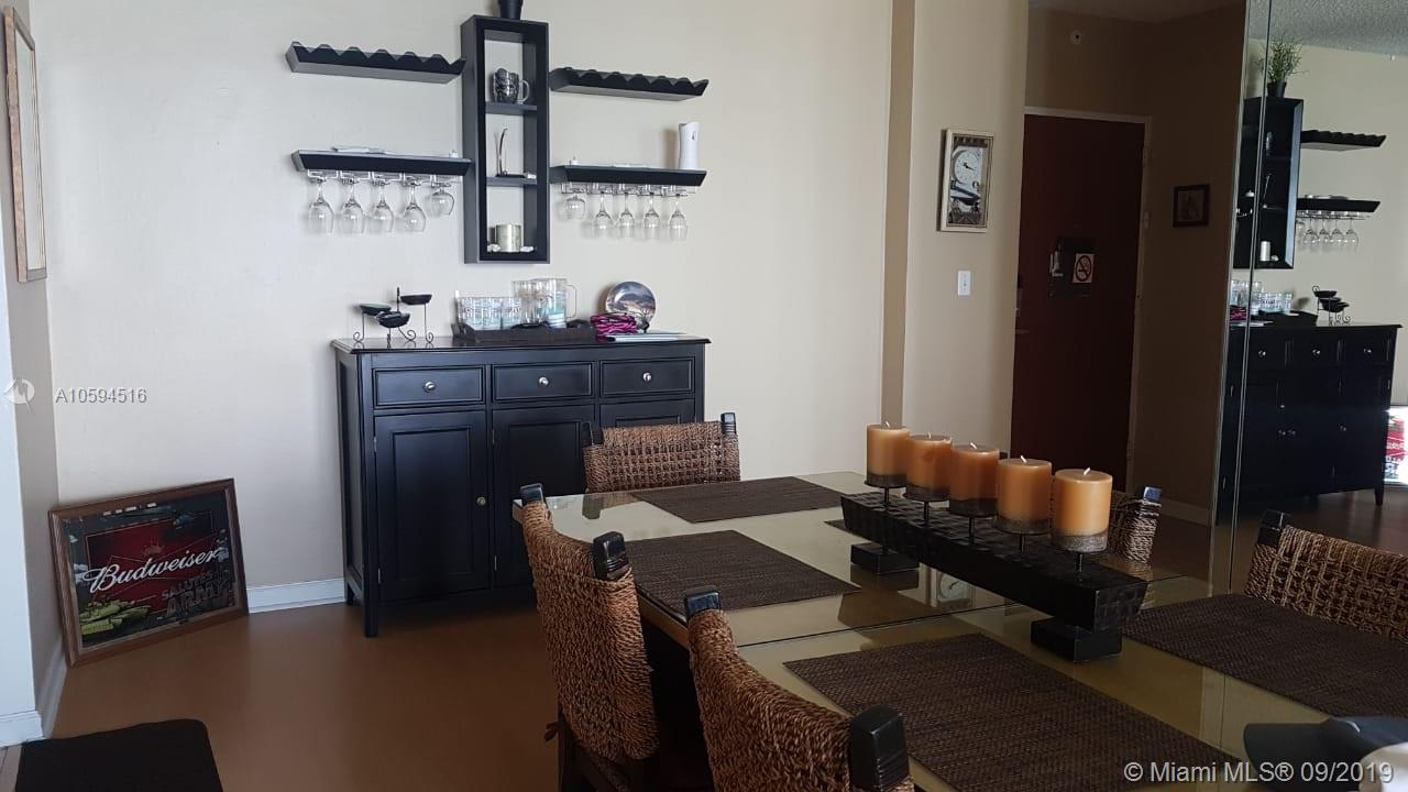 A dining room features a glass table, wicker chairs, a black sideboard, and wall-mounted shelving — 3901 S OCEAN DR # 8L, Hollywood FL 33019, HOLLYWOOD, FL