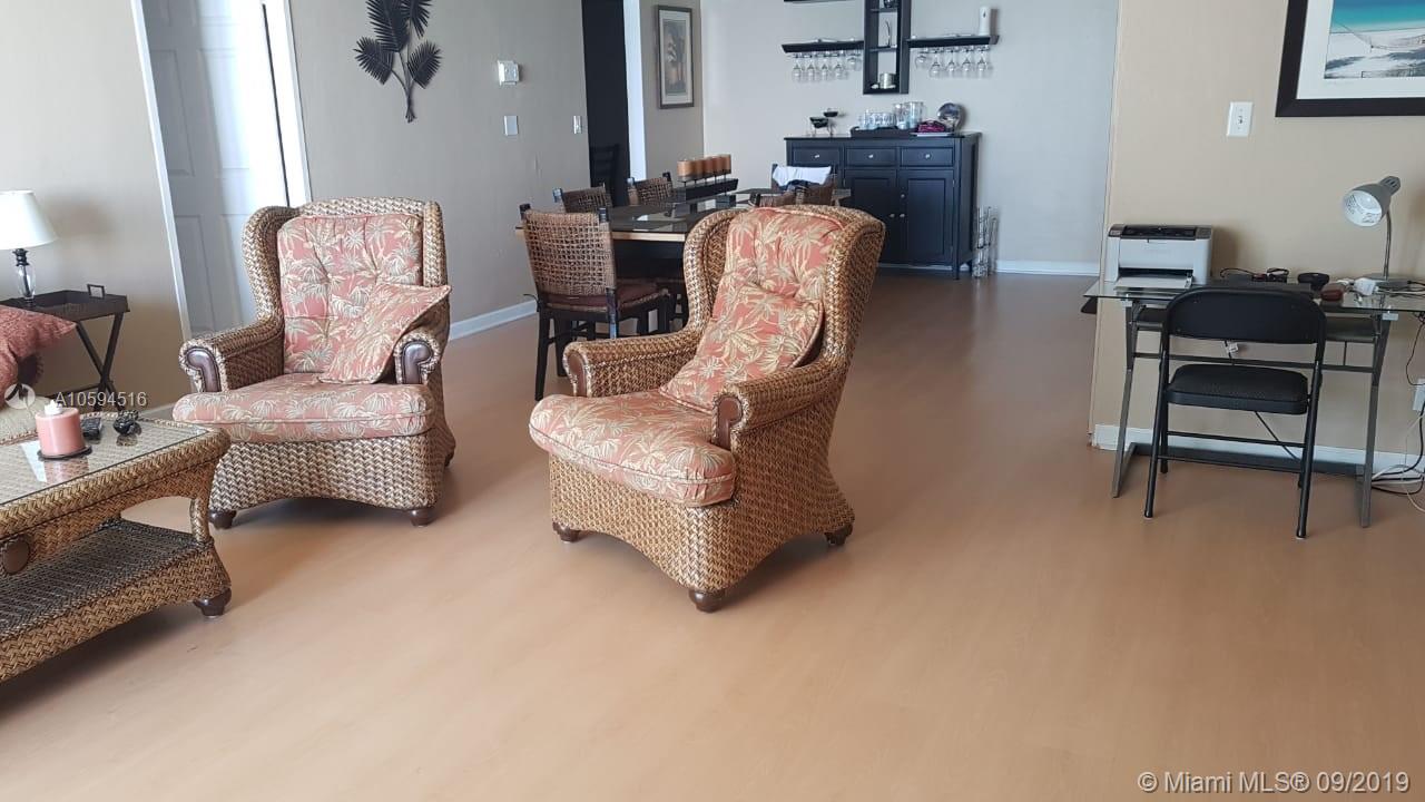 A living room features two wicker armchairs with floral cushions and a glass-topped desk — 3901 S OCEAN DR # 8L, Hollywood FL 33019, HOLLYWOOD, FL