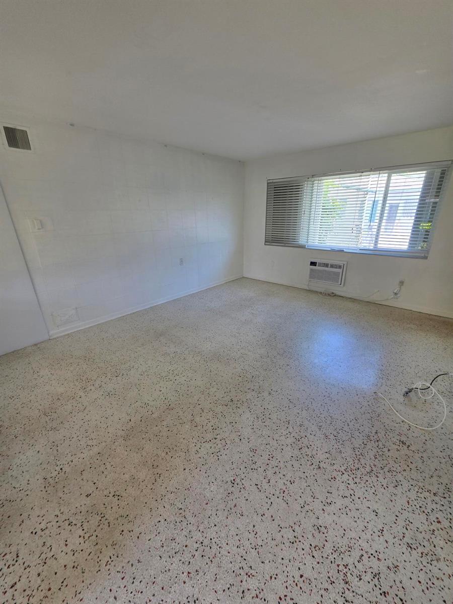 An empty room features white walls, a window with blinds, and speckled terrazzo flooring — 1216 Cabana Road # 1a, Singer Island FL 33404, SINGER ISLAND, FL