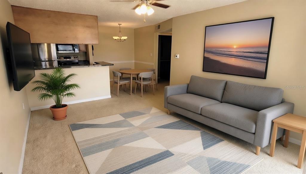 A living room with a gray sofa, geometric rug, and an adjacent dining area — 302 LAKE PARSONS GREEN UNIT 102, BRANDON, FL
