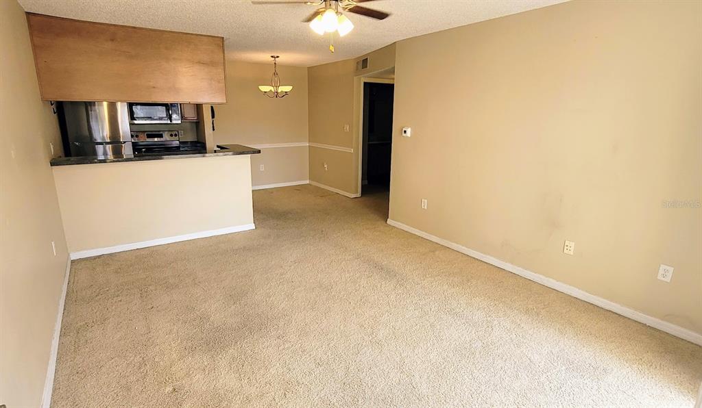 A carpeted living room opens to a kitchen with a breakfast bar and dining area — 302 LAKE PARSONS GREEN UNIT 102, BRANDON, FL
