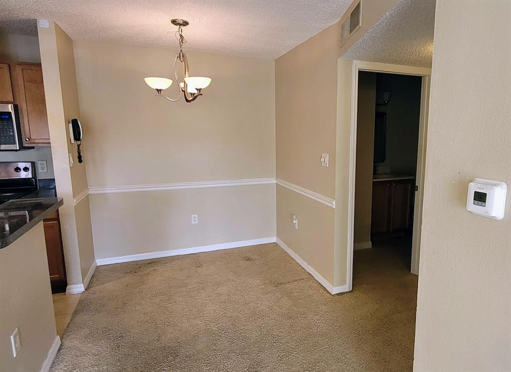 A dining area features beige carpet, tan walls with chair rail molding, and a chandelier — 302 LAKE PARSONS GREEN UNIT 102, BRANDON, FL