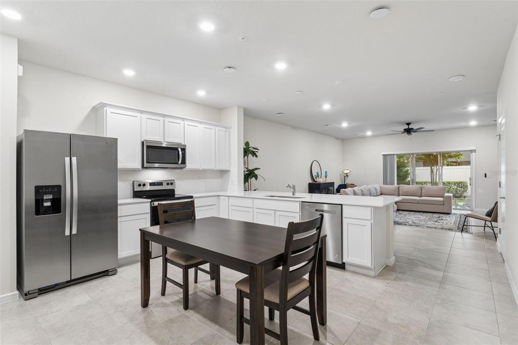 A modern kitchen with white cabinets, stainless steel appliances, and a dining table — 2017 CANNY COVE, WINTER PARK, FL