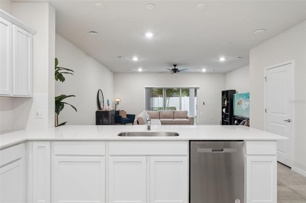 A kitchen island with a stainless steel sink and dishwasher overlooks an open-concept living area — 2017 CANNY COVE, WINTER PARK, FL