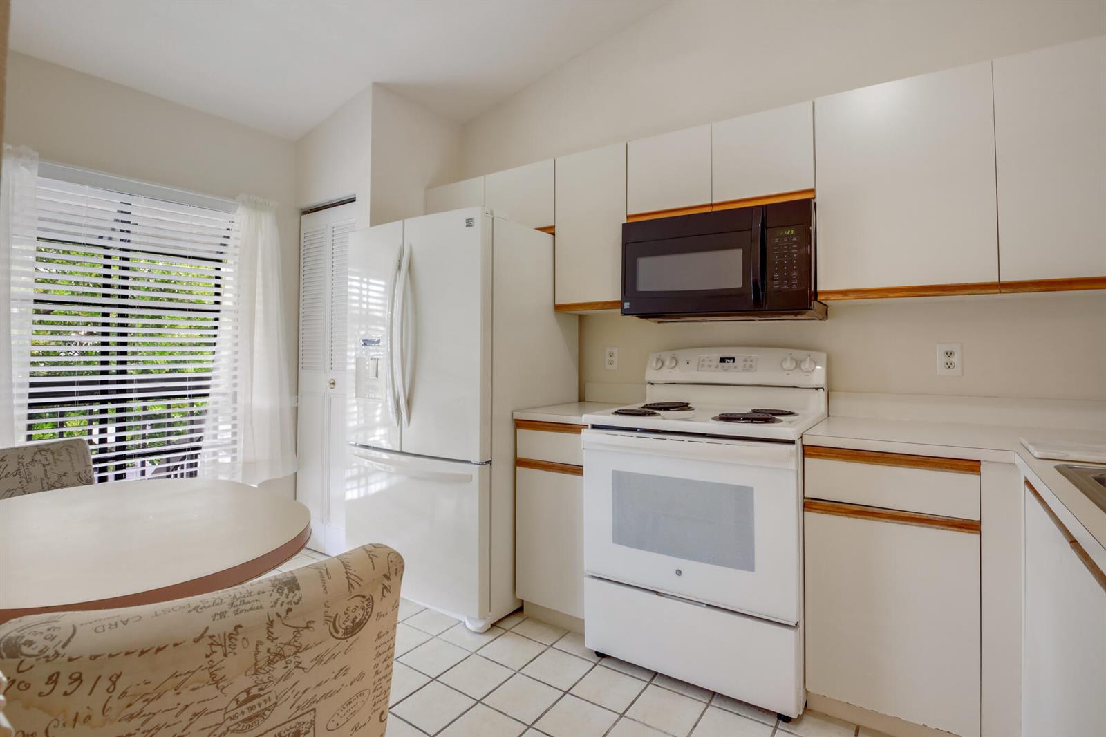 A kitchen features white cabinets, a white stove, a black microwave, and a white refrigerator — 3340 Lucerne Park Drive, FL 33467, FL
