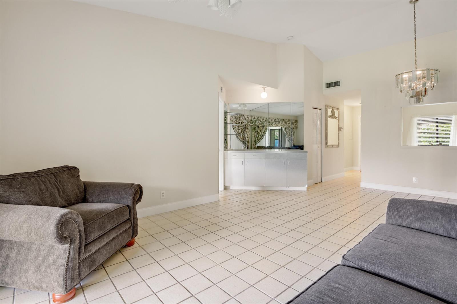 A living room with light tile floors, a grey armchair, a grey sofa, and a wet bar — 3340 Lucerne Park Drive, FL 33467, FL