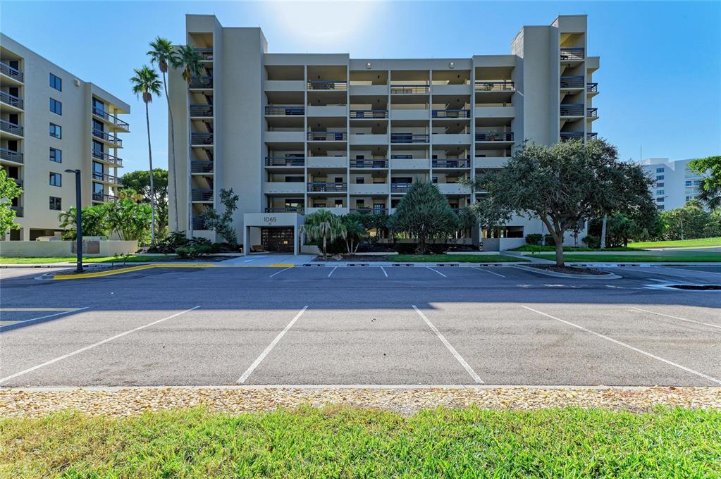 A multi-story apartment building features balconies and a parking lot in the foreground — 1065 GULF OF MEXICO DRIVE UNIT 201, LONGBOAT KEY, FL
