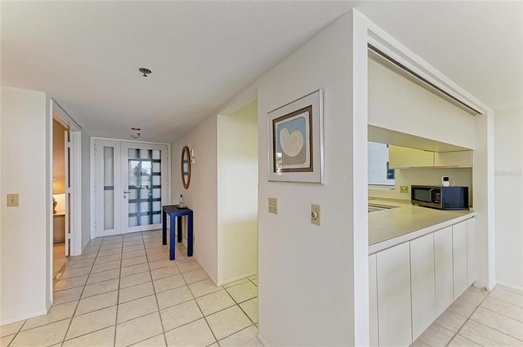 A tiled entryway leads to a kitchen with white cabinets and a microwave — 1065 GULF OF MEXICO DRIVE UNIT 201, LONGBOAT KEY, FL